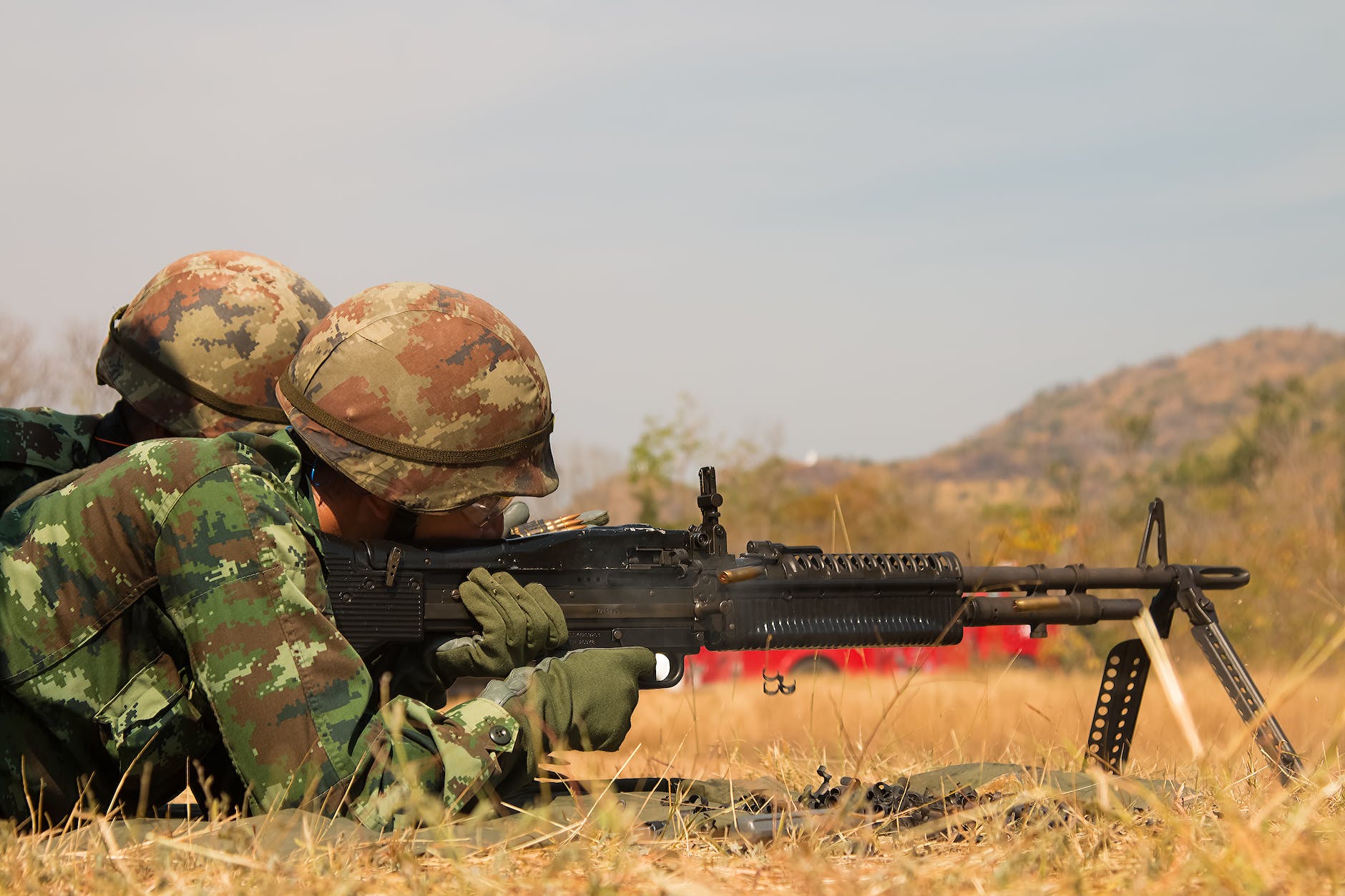 man lying forward using rifle at the field during day